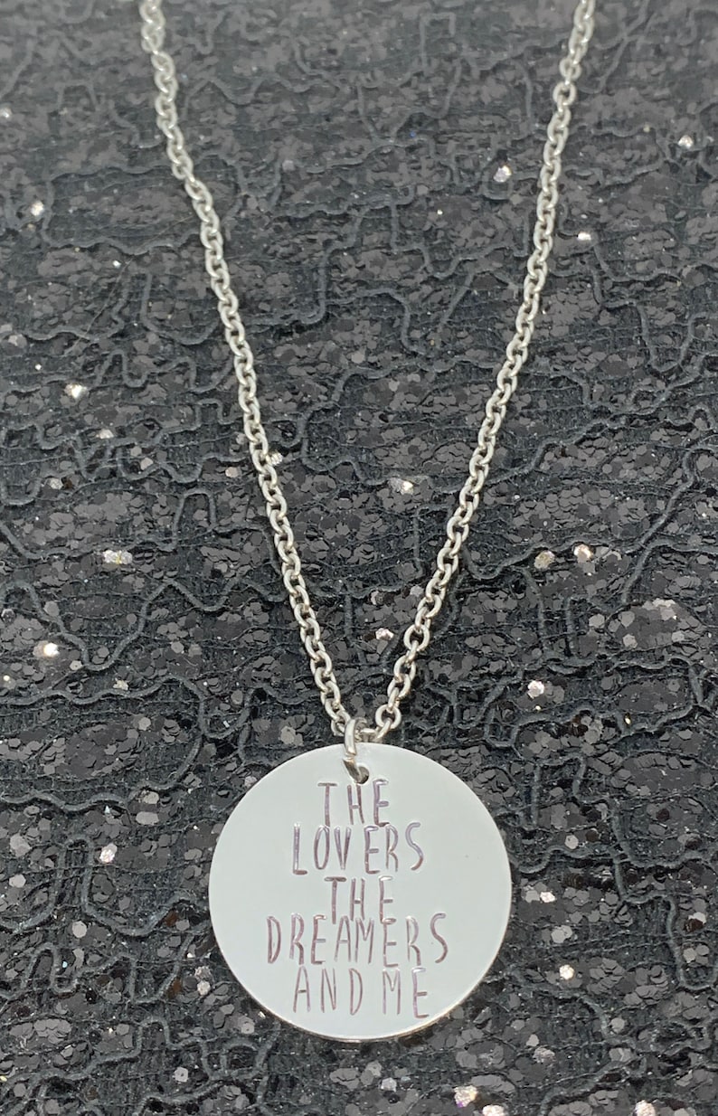 May include: A silver necklace with a round pendant that says "The Lovers The Dreamers And Me".