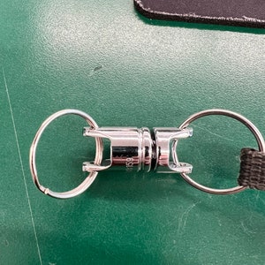 May include: A silver metal key chain with two rings and a spring-loaded clip. The clip has a small inscription that reads "59".