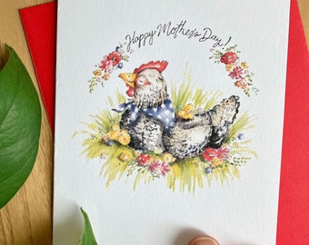 May include: A white card with a watercolor illustration of a hen with chicks surrounded by flowers. The text "Happy Mother's Day!" is written in black cursive at the top of the card.