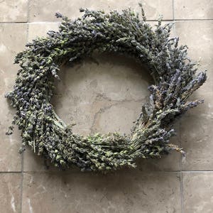 May include: A dried lavender wreath with purple and green hues. The wreath is made of natural lavender stems and is perfect for adding a touch of rustic charm to your home decor.
