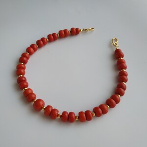 May include: A red coral bead bracelet with gold accents and a lobster clasp closure.