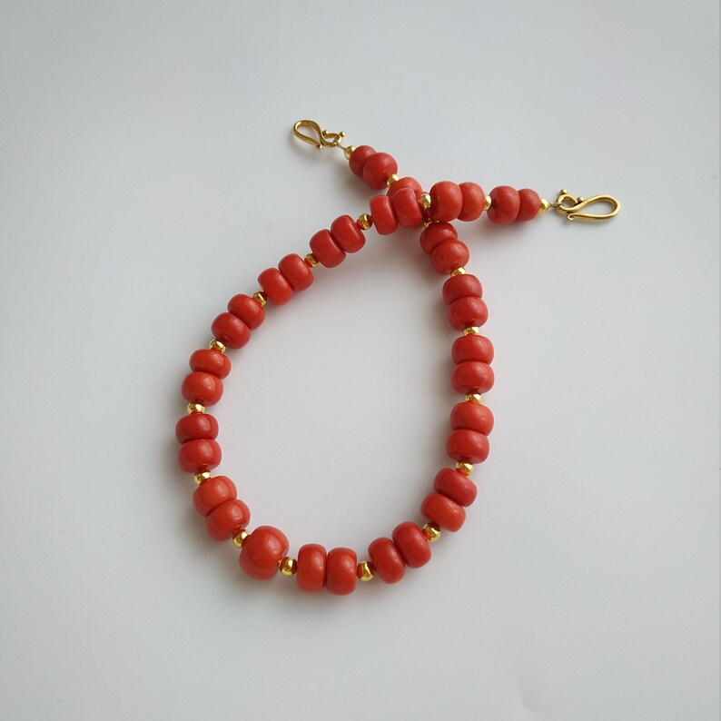 May include: A red coral beaded necklace with gold accents and clasps.