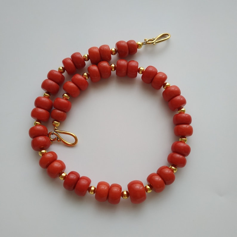 May include: A red coral beaded necklace with gold accents and a gold clasp.
