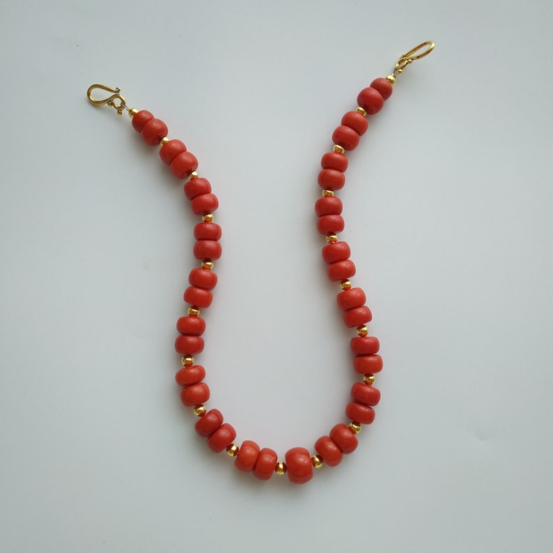 May include: A red coral beaded necklace with gold accents and clasps.