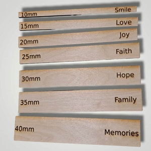 May include: Seven wooden strips with different lengths, ranging from 10mm to 40mm, each with a word engraved on it. The words are "Smile", "Love", "Joy", "Faith", "Hope", "Family", and "Memories".