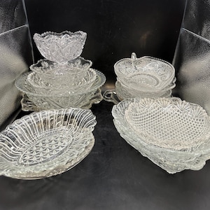 May include: A set of six clear glass bowls with intricate patterns. The bowls are stacked and arranged on a dark surface.