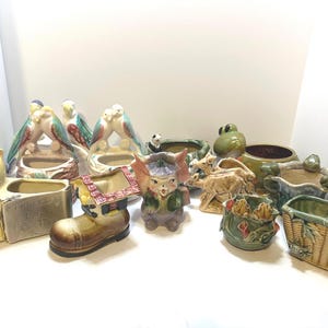 May include: A collection of vintage ceramic planter pots featuring various animal and bird designs. The planters are in shades of green, brown, yellow, and blue. Some of the planters have a glazed finish, while others have a matte finish.