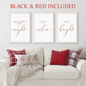 May include: Three white framed prints with red text on a white couch with two red and white plaid pillows and one pillow with the text 'Ho Ho Ho' in red. The prints read 'Silent Night Holy night', 'All is calm', and 'All is bright'.