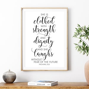 May include: A black and white printable wall art print with a quote about strength and dignity. The quote reads "She is clothed with strength and dignity and she laughs without fear of the future. Proverbs 31:25".