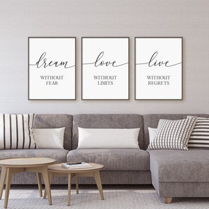 May include: Three black framed prints with white backgrounds and black calligraphy. The prints read "dream without fear", "love without limits", and "live without regrets".