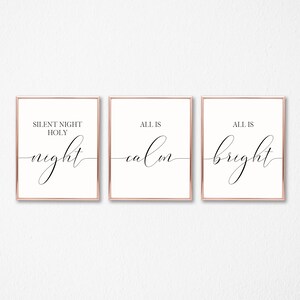 May include: Three framed prints with rose gold borders. The prints feature elegant black script on a cream background. The text on the prints reads "SILENT NIGHT HOLY night", "ALL IS calm", and "ALL IS bright".