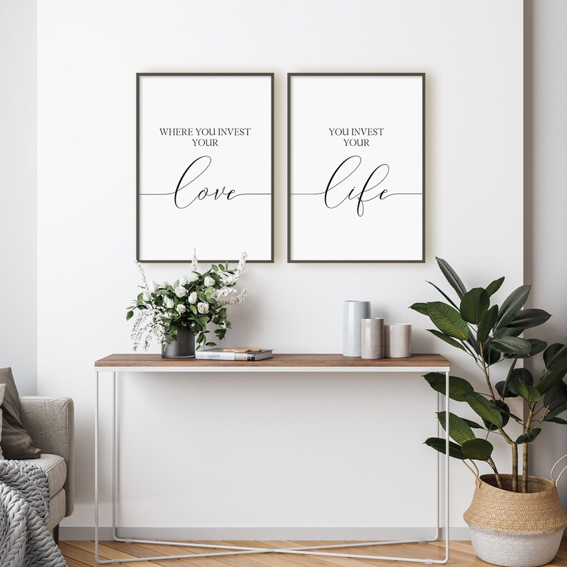 Pu&ograve; includere: Due stampe incorniciate nere con sfondi bianchi e testo nero. Il testo sulla stampa di sinistra recita "Where you invest your love" e il testo sulla stampa di destra recita "You invest your life". Le stampe sono appese a una parete bianca sopra un tavolo consolle in legno con una cornice in metallo bianco. Ci sono fiori bianchi in un vaso sul tavolo e una pianta in vaso con foglie verdi in un cesto intrecciato.