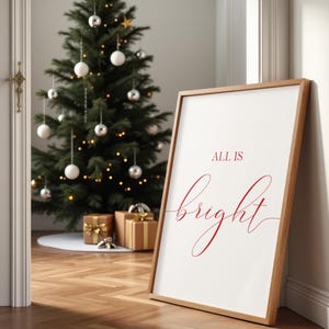 May include: A framed print with the words "ALL IS bright" in red script leans against a wall. A decorated Christmas tree with ornaments and lights is in the background. Several wrapped gifts are at the base of the tree.