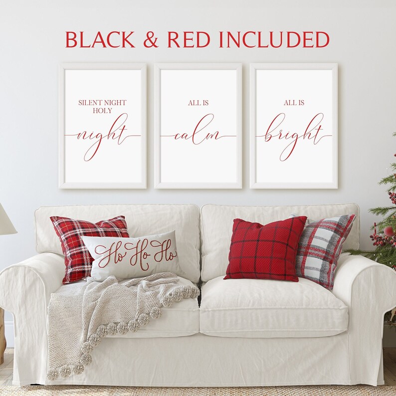 May include: Three white framed prints with red text on a white couch with two red and white plaid pillows and one pillow with the text 'Ho Ho Ho' in red. The prints read 'Silent Night Holy night', 'All is calm', and 'All is bright'.