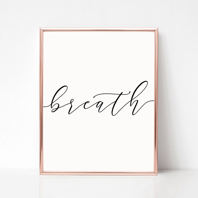 K&ouml;nnte beinhalten: Ein gerahmter Druck mit dem Wort "breath" in eleganter Schreibschrift. Der Rahmen ist in Ros&eacute;gold.