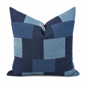 May include: A square throw pillow featuring a patchwork design made of denim fabric. The pillow displays a repeating checkerboard pattern alternating between dark navy blue and light blue denim squares, creating a structured geometric appearance.