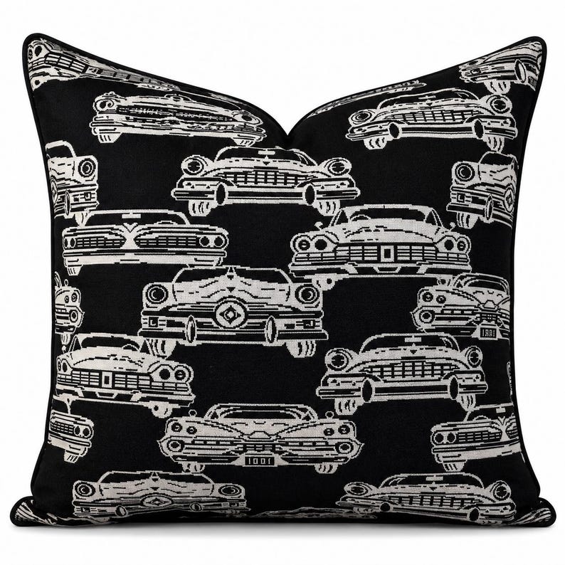 May include: A square throw pillow featuring a repeating pattern of white vintage cars on a solid black background. The design showcases various front-facing classic automobiles with detailed grilles, headlights, and bumpers, finished with black piping.