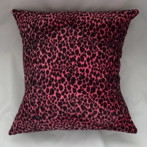 Puede incluir: Almohada de tiro de estampado de leopardo rosa y negro. La almohada est&aacute; hecha de una tela suave y de felpa.