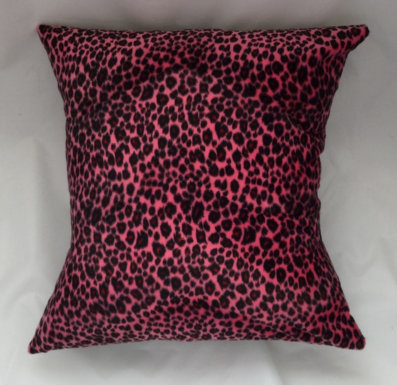 Puede incluir: Almohada de tiro de estampado de leopardo rosa y negro. La almohada est&aacute; hecha de una tela suave y de felpa.