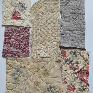 Puede incluir: Una colección de seis retazos de tela acolchada con diversos patrones, incluyendo motivos florales rojos y azules, un estampado de damasco granate, un diseño de hojas beige y un pequeño patrón floral gris, todos con costuras y bordes deshilachados.