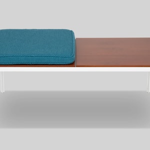 May include: A modern bench with a teal cushion and a wooden tabletop. The bench has a white metal frame. The cushion is rectangular and has a textured surface. The wooden tabletop is rectangular and brown.