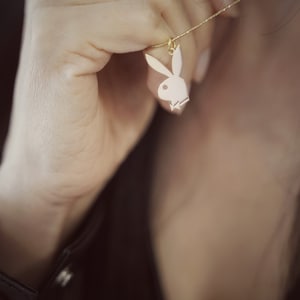 May include: A gold chain necklace with a white bunny pendant. The bunny is a popular symbol and is often associated with a well-known brand.