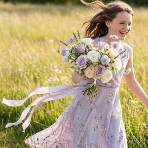 May include: A young person in a lavender dress runs through a field of tall grass, holding a bouquet of white, lavender, and yellow flowers. Long lavender ribbons trail from the bouquet. The dress has a floral pattern.