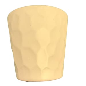 Puede incluir: Una taza de cerámica de color amarillo claro con una superficie texturizada geométrica. La taza tiene forma cilíndrica con una parte superior ligeramente ensanchada. El exterior presenta un patrón repetitivo de facetas angulares irregulares.