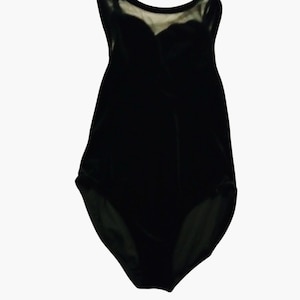 May include: A black velvet bodysuit featuring a sleeveless design with a sheer mesh panel at the upper chest and neckline. The garment has a sweetheart-style bodice construction and high-cut leg openings, crafted from a soft, dark fabric.