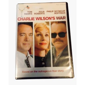 May include: DVD case for the movie "Charlie Wilson's War" featuring Tom Hanks, Julia Roberts, and Philip Seymour Hoffman. The cover has a white background with the movie title in large red letters and the tagline "Based on the outrageous true story."