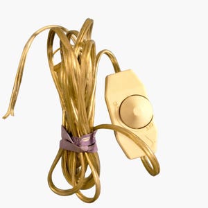 May include: A coiled gold electrical cable with a cream-coloured inline switch. The switch has a rotary dial with "ON" and "OFF" markings. A purple ribbon secures the cable.