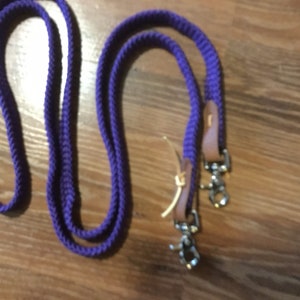 May include: Purple braided leather reins with brown leather accents and silver snap hooks.
