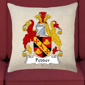 May include: A beige pillow with a crest featuring a red and black shield with a yellow dog, surrounded by gold and red foliage. The text "Pedder" is written on a white banner below the crest.