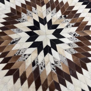 Pode incluir: Um tapete de pele de vaca com um design de estrela. O tapete apresenta um padr&atilde;o geom&eacute;trico de formas de diamante em tons de castanho, preto, creme e padr&otilde;es salpicados. O tapete &eacute; um revestimento de ch&atilde;o decorativo.