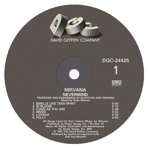 Peut inclure: Un disque vinyle noir et blanc avec le titre "Nirvana Nevermind" et la liste des pistes de l'album. Le disque est de la David Geffen Company et de Sub Pop Records.