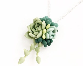 May include: A silver chain necklace with a green and light green succulent pendant. The pendant is made of polymer clay and has a realistic look.