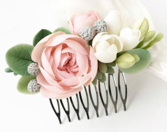 May include: A pink and white floral hair comb with a silver comb. The comb is decorated with pink roses, white freesia, and green leaves.