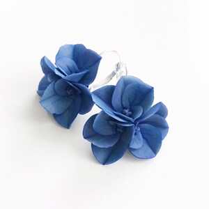 May include: A pair of blue flower hoop earrings. The earrings are made of polymer clay and are shaped like hydrangeas. The earrings are lightweight and comfortable to wear.