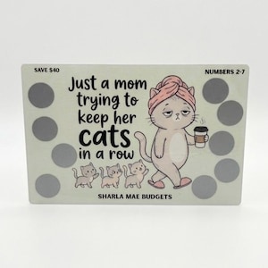 May include: A light green savings tracker with a cartoon cat design. The cat, wearing a pink towel and holding coffee, is walking with three small kittens. Text reads "Just a mom trying to keep her cats in a row."