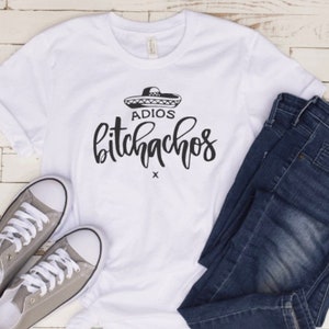 May include: White t-shirt with a black graphic that says "Adios Bitchachos" with a sombrero above the text.