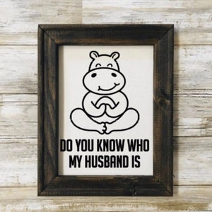 May include: A framed print with a black and white illustration of a hippopotamus sitting in a yoga pose. The text below the image reads "Do you know who my husband is?"