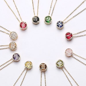 May include: Twelve gold necklaces with zodiac signs and colorful gemstones. Each necklace features a different zodiac symbol and a corresponding gemstone.