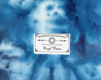 Könnte beinhalten: Ein blauer und weißer Batik-Leinenstoff mit einem weißen Etikett, auf dem "Norgrove Enterprises. Hand-dyed Linen Fat Quarter Royal Waters." steht.