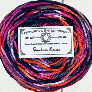 Puede incluir: Un ovillo de hilo de algodón de peso worsted teñido a mano en un patrón multicolor de naranja, morado, rosa y negro. El hilo está etiquetado como "Norgrove Enterprises" y "Samhain Soiree".