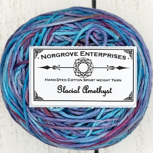 May include: A skein of hand-dyed cotton sport weight yarn in a blue, purple and pink colourway called "Glacial Amethyst" by NorGrove Enterprises.
