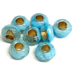 May include: A selection of light blue, faceted glass beads with gold detailing. The beads are cylindrical with a central hole, ideal for jewellery making or craft projects. Each bead has a diameter of approximately 1 cm.