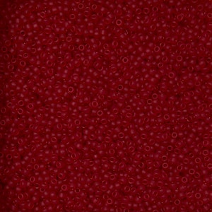 May include: A close-up of numerous small, round, dark red beads. The beads are tightly packed, filling the image. They have a slightly translucent quality, creating a rich, textured surface. Suitable for jewellery making and various craft projects.
