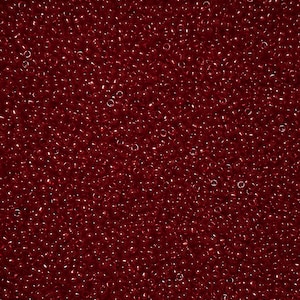 May include: A close-up of a mass of small, round, translucent beads. The beads are a deep, rich red colour, and they are scattered across the frame. The beads are uniform in size and shape, and they have a slight sheen.