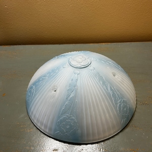 Może przedstawiać: Biało-niebieski szklany klosz lampy z kwiatowym wzorem. Klosz ma falisty brzeg i jest matowy.