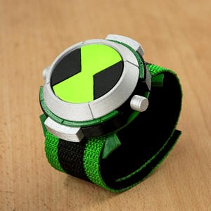 May include: A green and black wristwatch with a silver rim and a green alien symbol on the face. The watch has a black and green strap.
